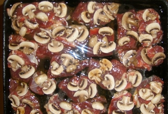 Сверху мяса раскладываем шампиньоны